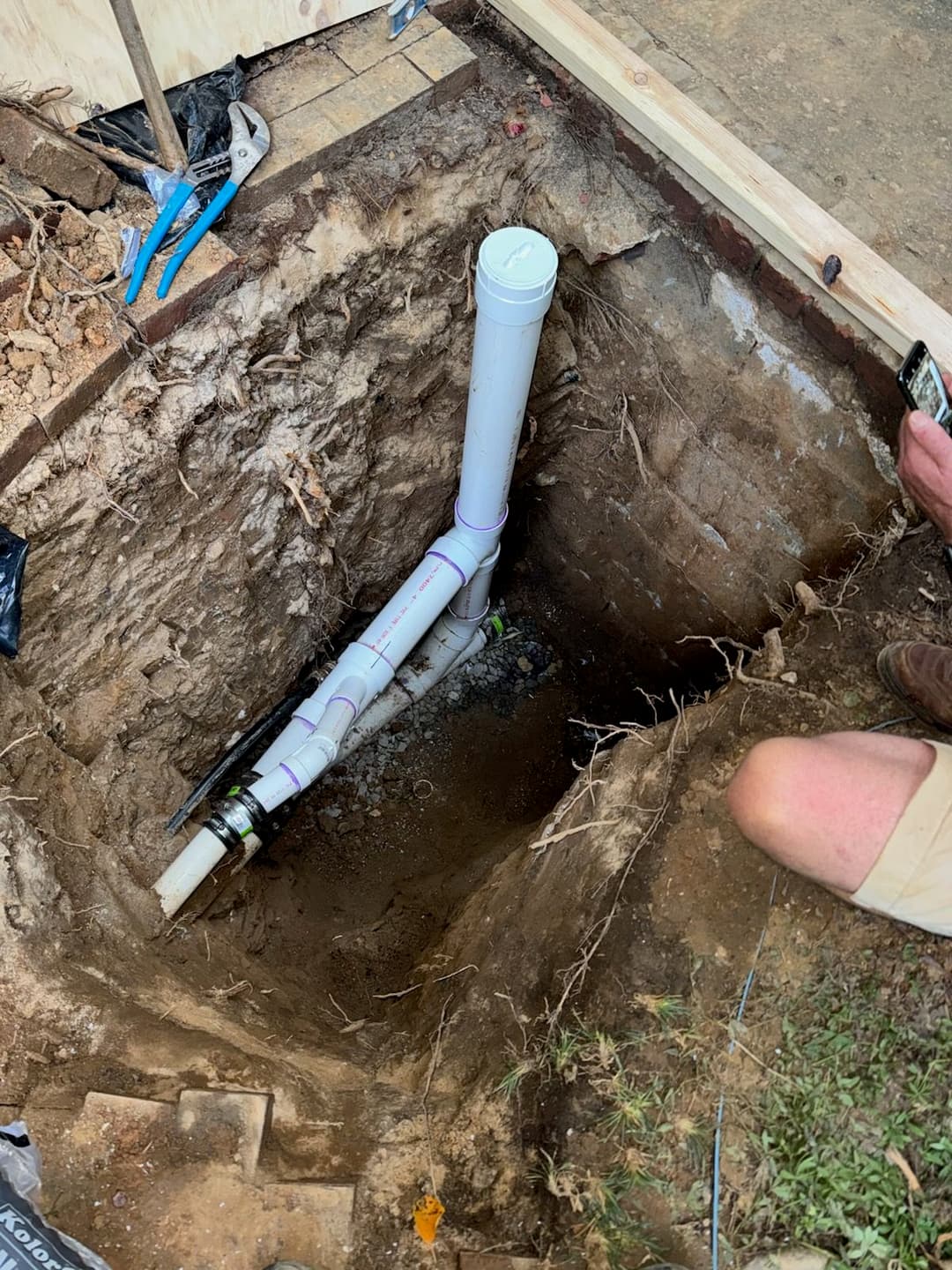 Excavated area showing PVC pipes for plumbing installation and repairs.