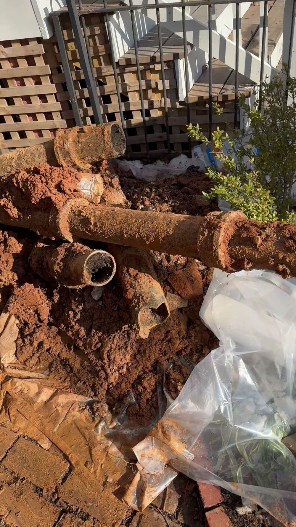 Rusty pipes on a construction site surrounded by dirt and debris.