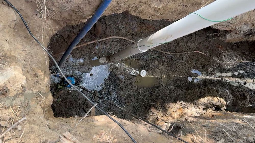 Excavation site showing pipes and water, highlighting a groundwater drilling operation.