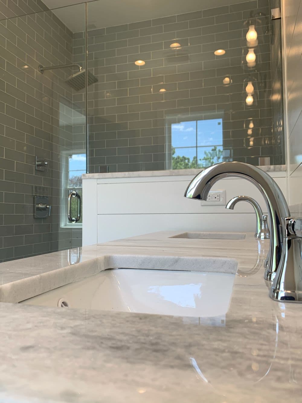 Modern bathroom with dual sinks, marble countertop, and glass shower enclosure.