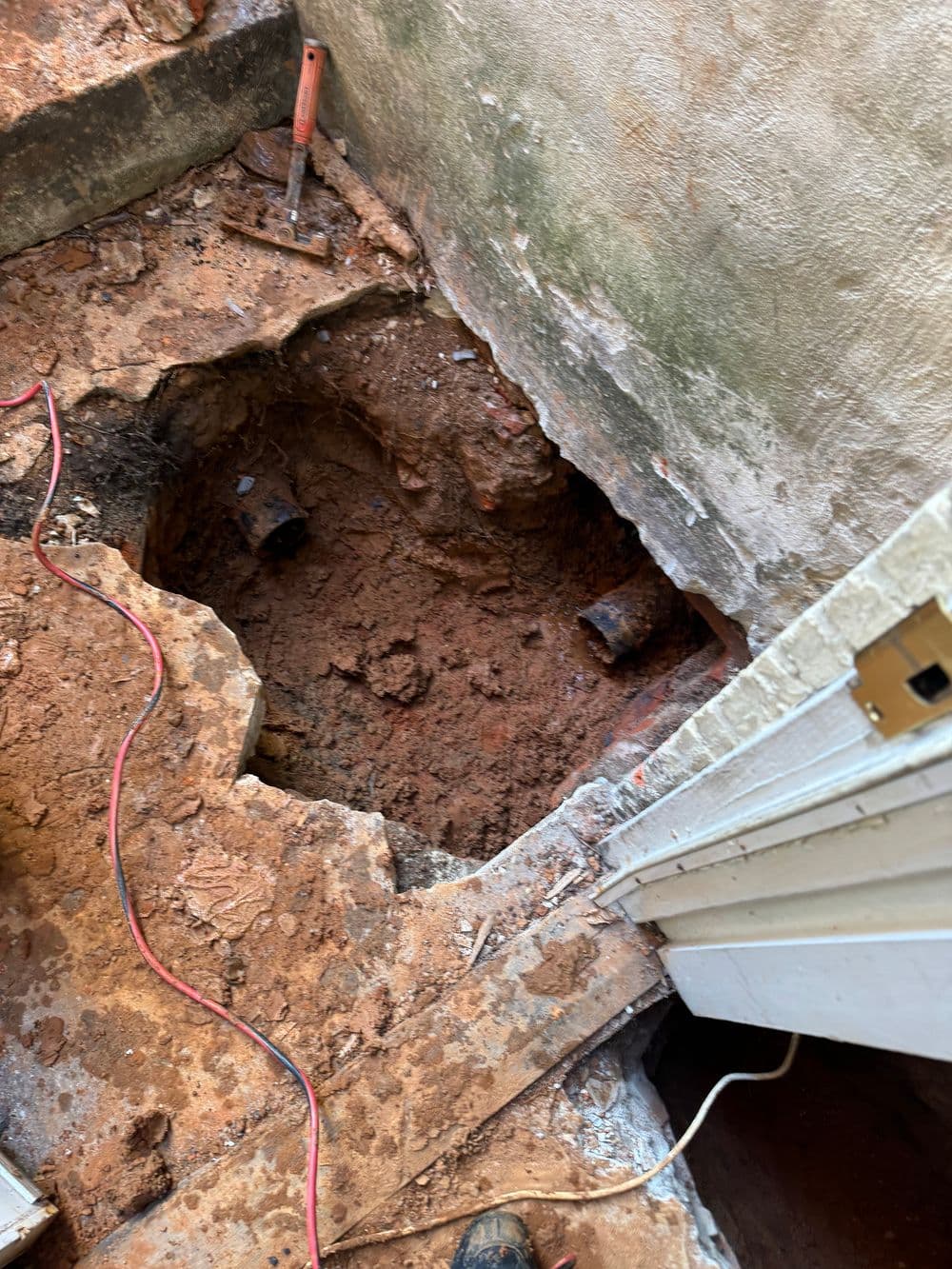 Excavated area showing dirt and pipes, indicating plumbing repair site.