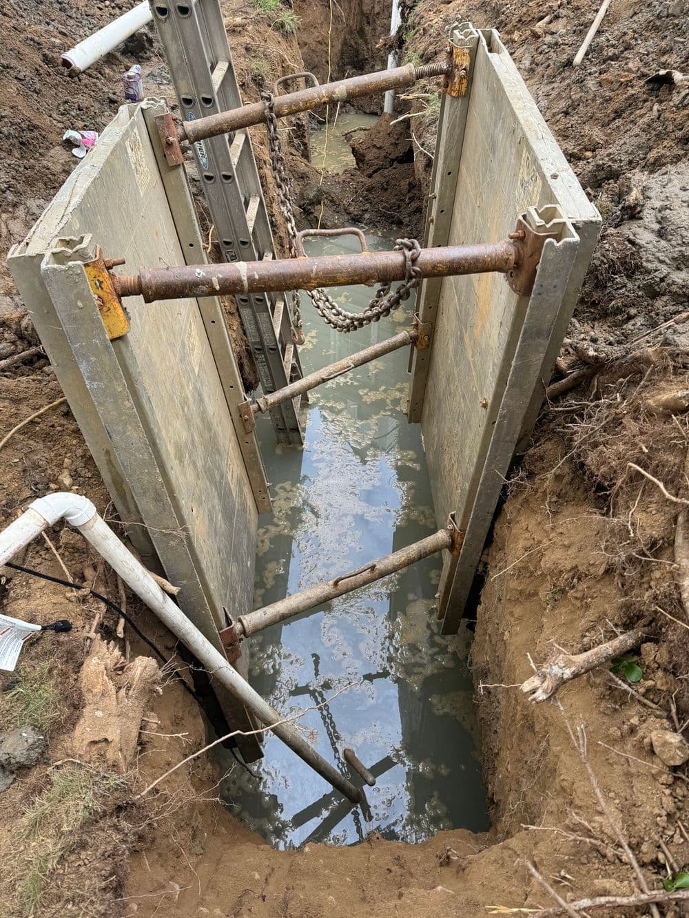 Concrete trench box in flooded excavation site for construction safety and stability.