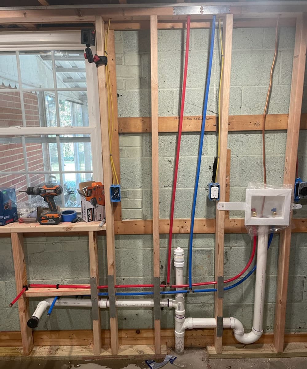 Plumbing installation with blue and red pipes on framed wall in a home renovation project.
