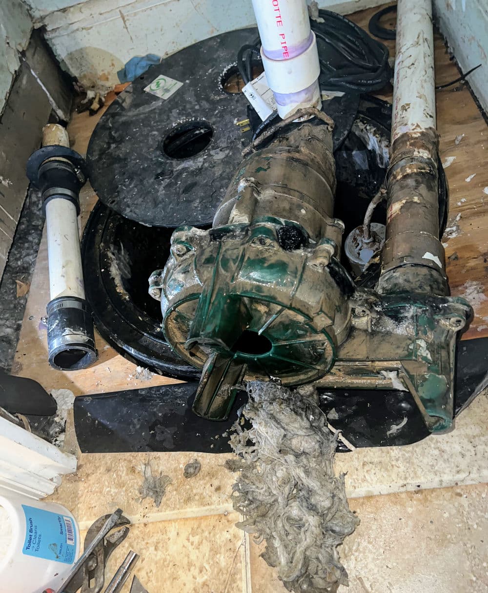 Sump pump with debris buildup in a residential basement setting, highlighting maintenance needs.